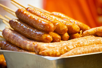 a sausage is being lifted by tongs and placed on a red-hot grill,