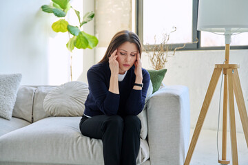 Mature sad woman experiencing stress, mental and physical pain, at home
