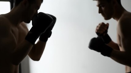 Silhouette of two people practicing boxing in gym - Powered by Adobe