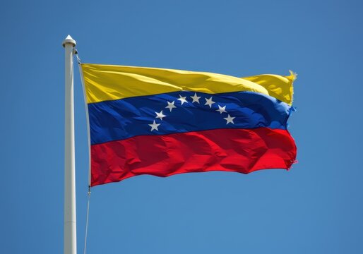 Venezuelan flag waving against a clear blue sky, symbol of national identity
