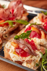 Assorted Italian bruschetta served on rustic bread with toppings like octopus, cured meats, ricotta, tomatoes, and anchovies, close-up view.