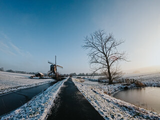 A frozen country road specific to rural Holland during a frosty winter. Walking path along the famous Dutch canals and windmills