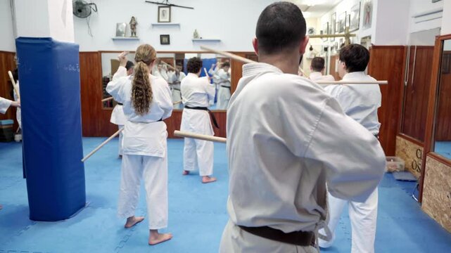 Martial arts students practicing jo staff techniques in dojo