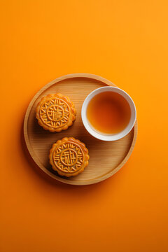Mooncakes with tea in a wooden plate on an orange backdrop