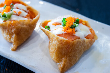 Japanese inari sushi topped with fresh salmon, mayonnaise, tobiko, and green onion. A colorful and appetizing dish, perfect for Asian cuisine, food menus, and restaurant promotions.