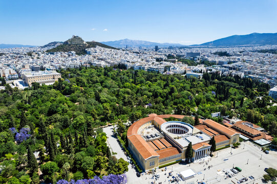 Aerial view of the Zappeion Mansion and National Garden in Athens, Greece, with Mount Lycabettus and the city's urban landscape in the background