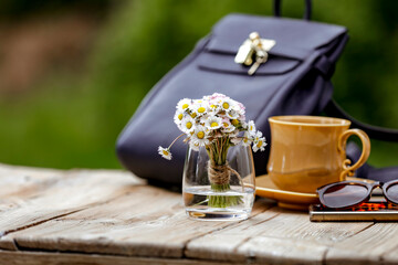 Spring or summer composition with female stuff on wooden garden table with natural outdoor green...