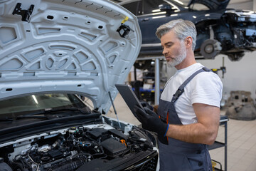 Mechanic with tablet in auto repair workshop