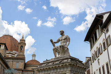 Obraz premium Statue of Giovanni delle Bande Nere in Piazza San Lorenzo, with the domes of the Basilica in the background, Florence, Italy