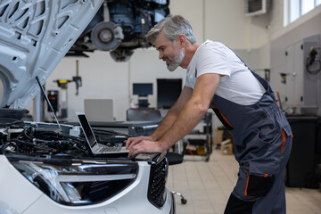 Mechanic performing diagnostics with laptop