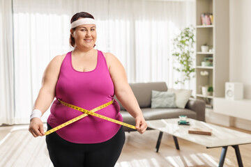 Happy plus size woman measuring waist