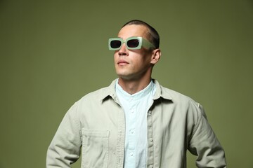 Fashionable portrait of handsome man in stylish outfit on green background