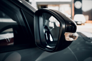 A side mirror of a modern car and an integrated turn signal, in a dealership or showroom.