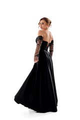 Fototapeta premium Elegant woman in a stunning black evening gown poses gracefully against a white backdrop