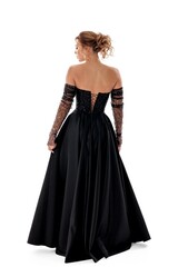 Elegant woman in a black evening gown with detailed back design posing gracefully