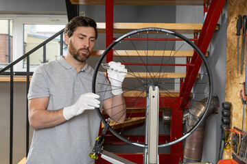 Mechanic in white gloves with bicycle wheel
