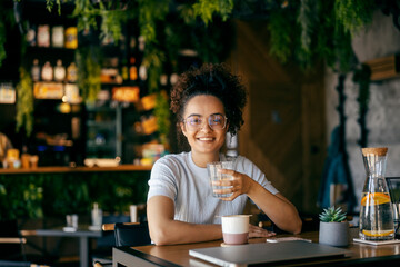 Portrait of multicultural girl drinking fresh glass of water and smiling at camera.