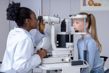 Ophthalmologist checking girls vision by using optical medical equipment