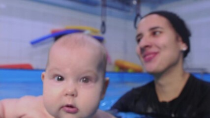 Instructor introducing a baby to water in an indoor pool