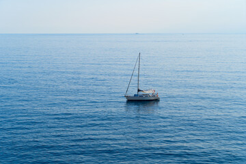 A serene, tranquil sailboat slowly gliding gracefully over the calm, beautiful ocean waters on a...