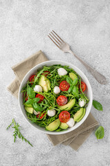 Fresh salad with arugula, mozzarella, tomatoes and avocado in a bowl. Healthy vegetarian dish.