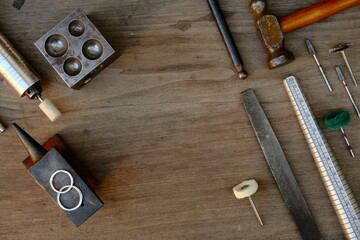 Jeweler's workplace. Top view of jeweler's workbenche with different tools on a wooden table with wedding rings . Goldsmith concept background