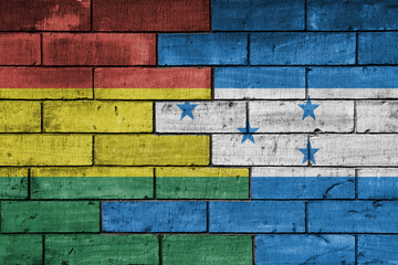 Fototapeta premium colourful painted big national flag of honduras and flag of bolivia on a massive old brick wall background. concept