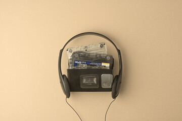 Vintage cassette player with classic headphones and audio tapes on beige background brings back...