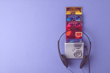 Stack of colorful minidiscs with classic silver player and headphones on purple background creates...