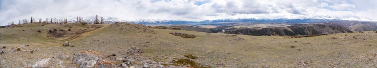 Panoramic view of Kurai Steppe with snow-covered North Chuysky Ridge in Altai Russia. Wide Siberian mountain landscape showcasing winter terrain and open plains.