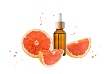 Amber bottle of face serum with vitamin C or essential oil and grapefruit slices with flying drops isolated on white background. Brown glass bottle covered bamboo wood as eco packaging.