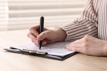 Fototapeta premium Woman underlining important information with marker at wooden desk indoors, closeup