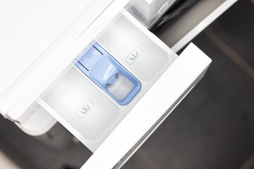 Drawer with blue detergent compartment in modern laundry room setup