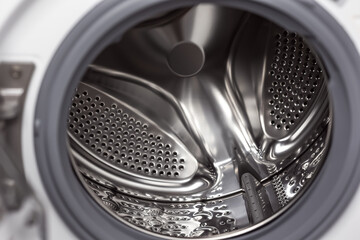 Interior view of a modern washing machine drum with stainless steel finish during laundry cycle