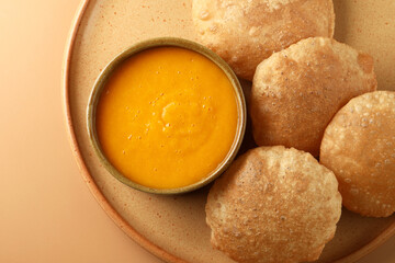 Mango pulp or Aam Rus served in a ceramic bowl with puri or deep fried indian bread