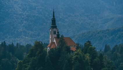 small church surrounded by green nature with tower on tiny island slovenia