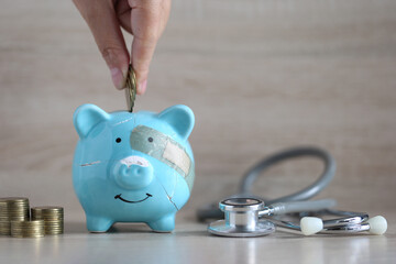 Piggy bank attached to the plaster on the head and stethoscope on wooden background, Save money for Medical insurance and Health care concept