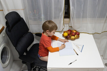 Preschooler kid drawing on notebook at home kitchen table