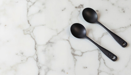 Two black serving spoons on a marble countertop  