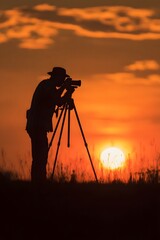 Photographer capturing a stunning sunset silhouette on a grassy hill, with vibrant clouds in the background