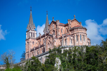 Obraz premium COVADONGA, SPAIN - APRIL 6, 2025: Covadonga in Asturias is a historic mountain village known for its sacred cave, basilica, and stunning natural surroundings.