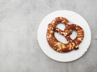 Freshly baked pretzel on white plate on gray background copy space