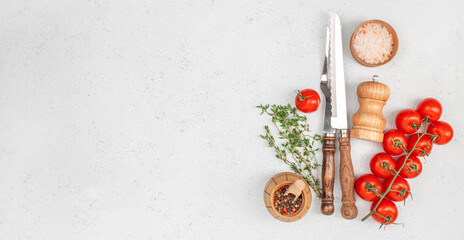 Set of fresh tomatoes, herbs, salt, pepper and kitchen knives arranged on light background for...