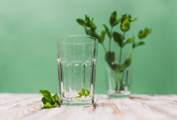 A glass with fresh mint leaves water on a table on a green background with copy space. Health benefits of peppermint water  concept.