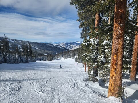 Pristine snow slopes in Colorado, blanketed in powdery white snow, inviting skiers and snowboarders to carve their way through the winter wonderland of the Rocky Mountains.