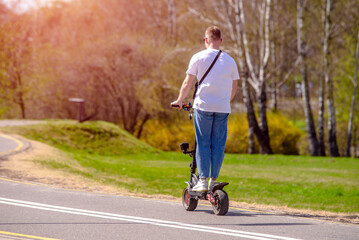 Obraz premium A guy rides an electric scooter in the summer Park 