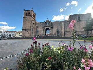 Beautiful red flowers decorating a charming plaza in front of a historic church in the picturesque city of Cusco, Peru. A vibrant blend of nature, colonial architecture, and cultural heritage in the h