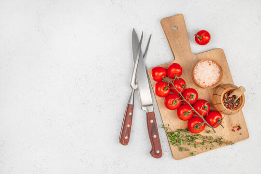 Top view of fresh tomatoes, herbs, salt, pepper and kitchen tools on wooden cutting board. copy space