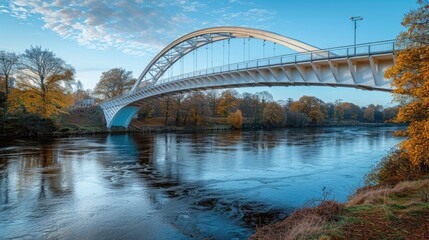 Obraz premium Modern White Bridge with Blue Underside - A sleek pedestrian bridge with a white upper structure and a light blue underside, spanning a calm river.