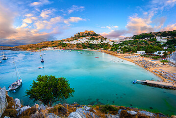 Lindos city, Rhodes island, Greece:  Panoramic view of Lindos bay at sunset with whitewashed village and the Acropolis, at Aegean Sea